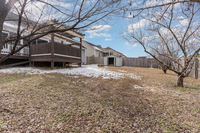 snowy yard featuring a wooden deck and a shed