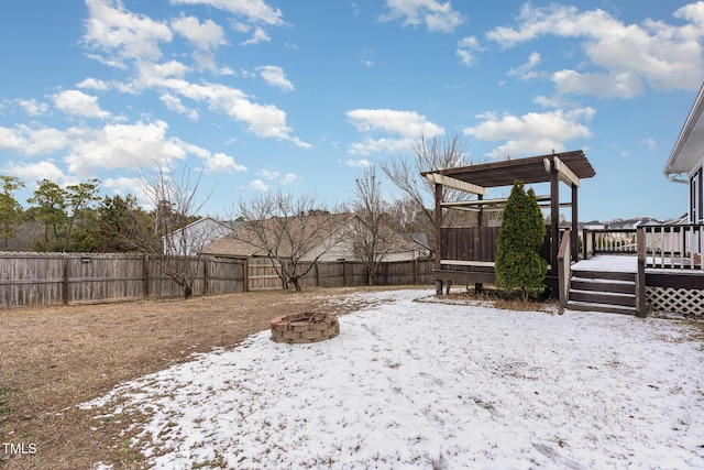 yard layered in snow with an outdoor fire pit and a deck