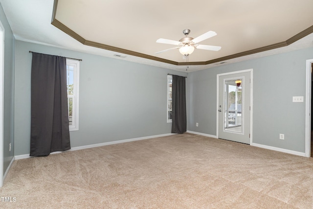 empty room featuring ornamental molding, light carpet, a wealth of natural light, and a tray ceiling