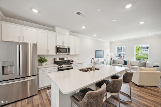 kitchen with sink, a breakfast bar area, appliances with stainless steel finishes, white cabinetry, and an island with sink