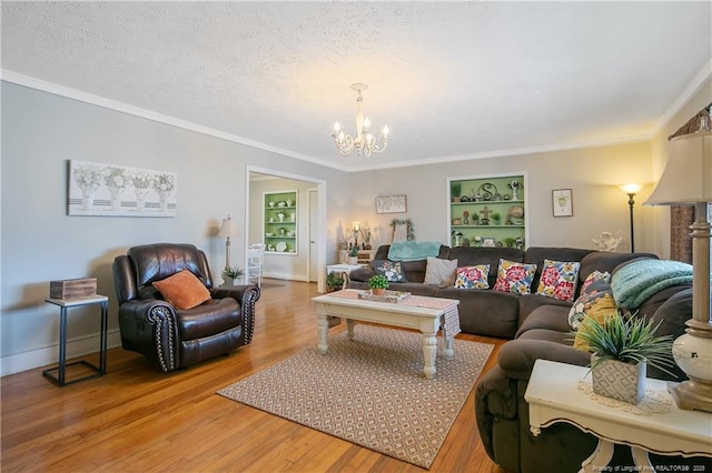 living room featuring ornamental molding, an inviting chandelier, a textured ceiling, and built in shelves