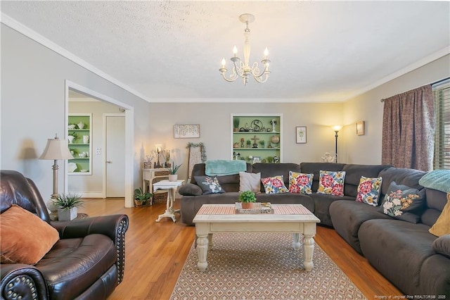 living room with ornamental molding, an inviting chandelier, light hardwood / wood-style floors, and built in shelves