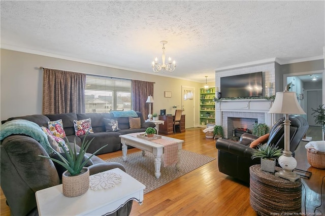 living room featuring ornamental molding, wood-type flooring, a brick fireplace, and a textured ceiling