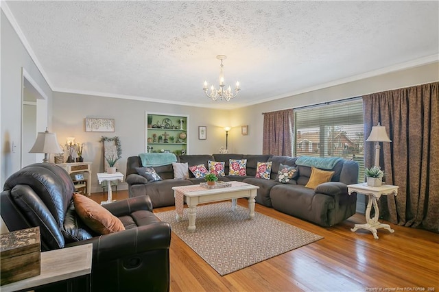 living room with built in features, hardwood / wood-style flooring, ornamental molding, a textured ceiling, and an inviting chandelier