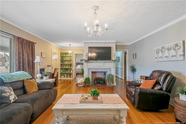 living room featuring a fireplace, crown molding, light hardwood / wood-style flooring, and a textured ceiling