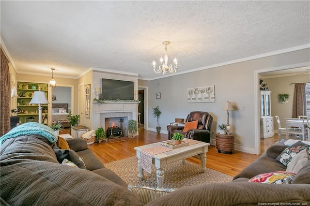 living room featuring ornamental molding, an inviting chandelier, a fireplace, and light wood-type flooring