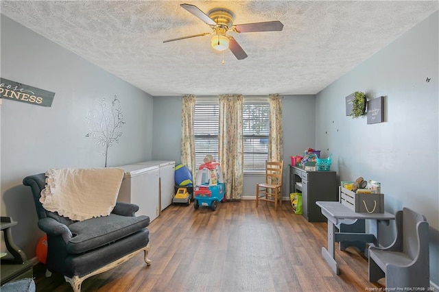 sitting room featuring dark hardwood / wood-style flooring, a textured ceiling, and ceiling fan