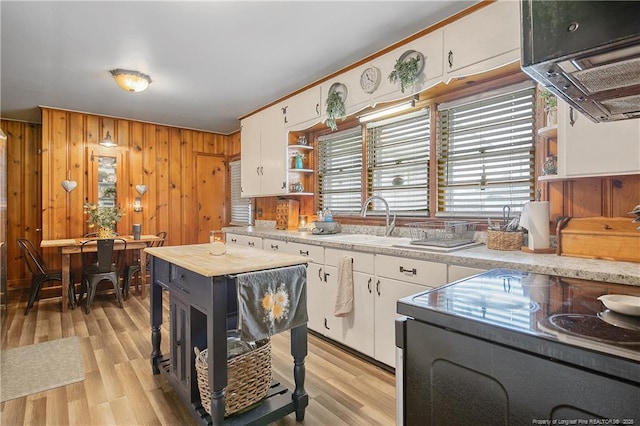 kitchen with sink, light hardwood / wood-style flooring, white cabinetry, wooden walls, and extractor fan