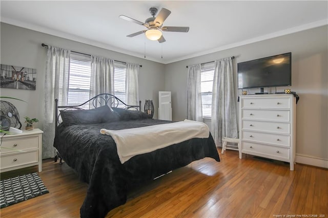 bedroom featuring ceiling fan, dark hardwood / wood-style flooring, and multiple windows