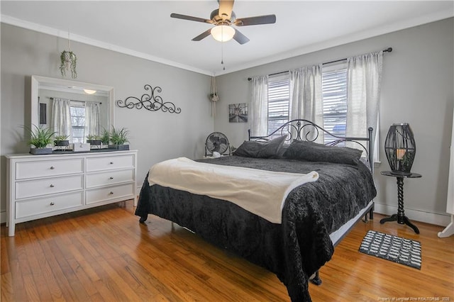 bedroom with hardwood / wood-style floors, ornamental molding, and ceiling fan