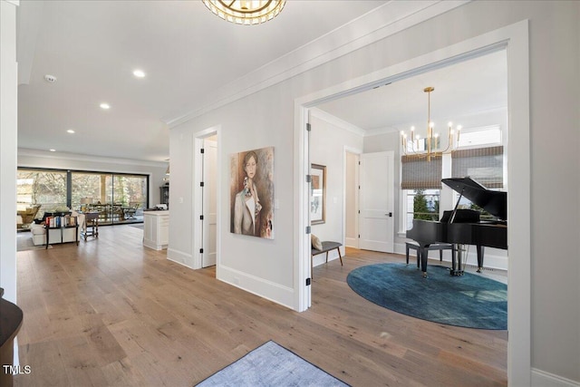 hallway with a notable chandelier, ornamental molding, and light wood-type flooring