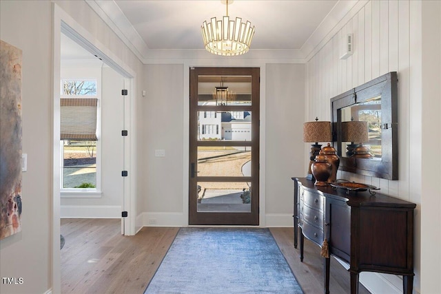 entrance foyer with an inviting chandelier, light hardwood / wood-style flooring, and ornamental molding