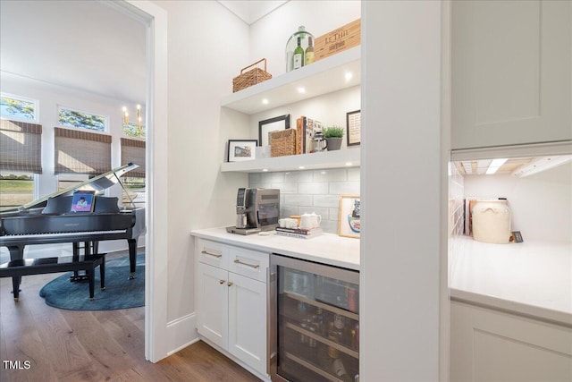 bar with decorative backsplash, beverage cooler, white cabinets, and light wood-type flooring