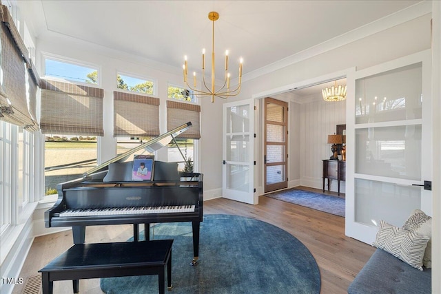 miscellaneous room with ornamental molding, a wealth of natural light, hardwood / wood-style floors, and an inviting chandelier