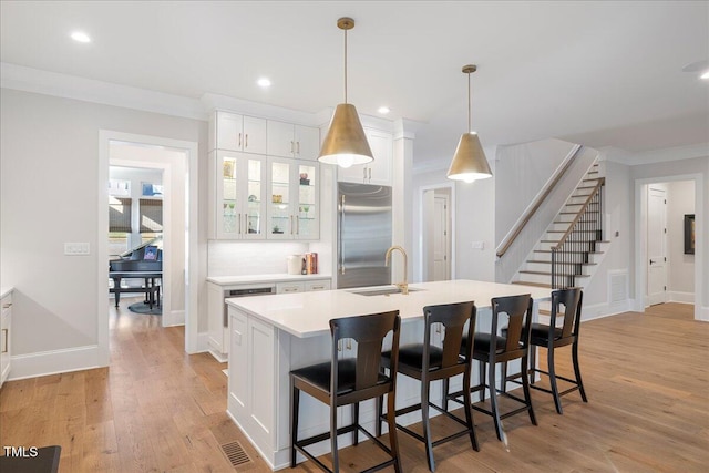 kitchen with white cabinetry, built in refrigerator, decorative light fixtures, and sink