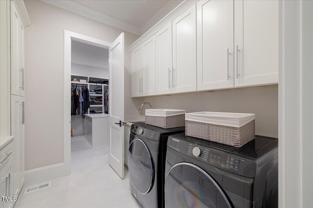 clothes washing area featuring cabinets, separate washer and dryer, and light tile patterned floors