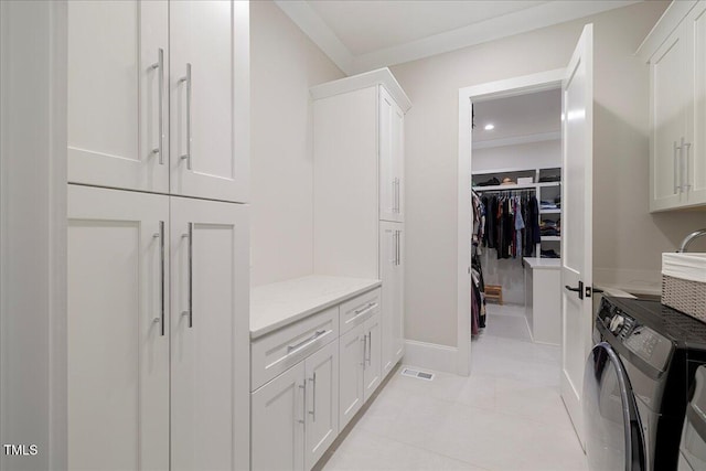 interior space featuring light tile patterned flooring, cabinets, and washer and dryer