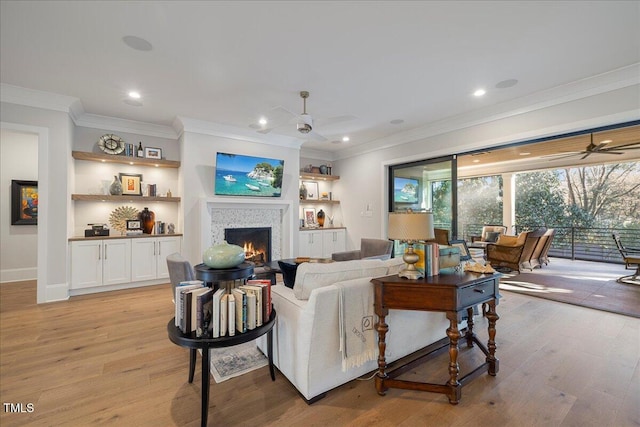 living room with ceiling fan, crown molding, and light hardwood / wood-style floors