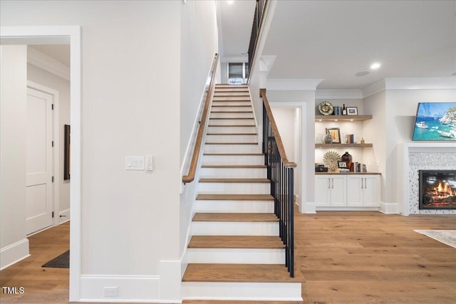 stairs featuring crown molding and hardwood / wood-style flooring