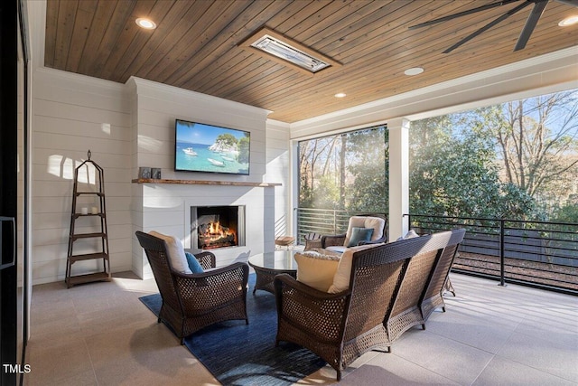 exterior space with ceiling fan, an outdoor fireplace, a skylight, and wooden ceiling