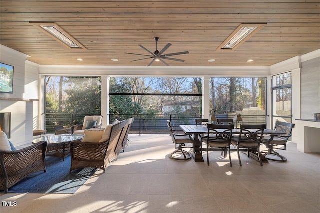 sunroom / solarium featuring wood ceiling, a skylight, and ceiling fan