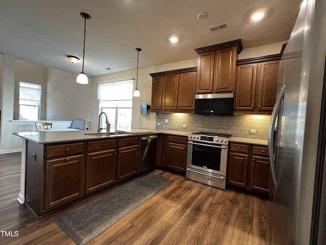 kitchen featuring stainless steel appliances, sink, decorative light fixtures, and kitchen peninsula