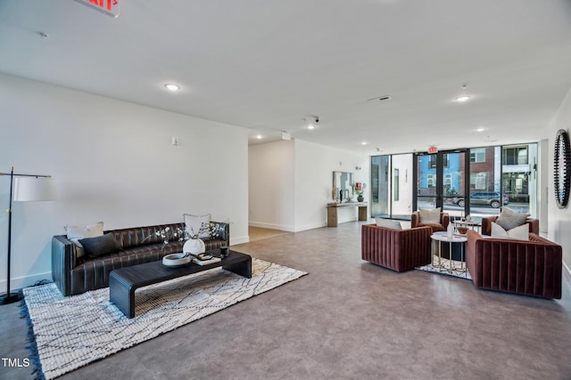 living area with floor to ceiling windows, recessed lighting, finished concrete flooring, and baseboards