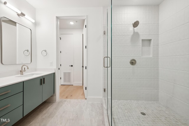 bathroom with vanity, wood finished floors, visible vents, and a stall shower