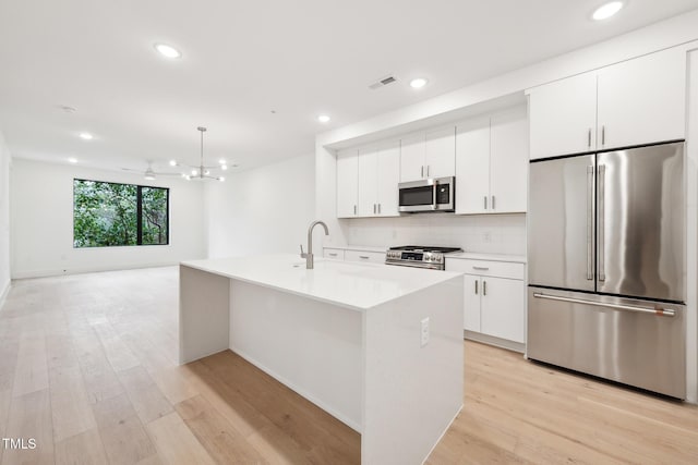 kitchen featuring stainless steel appliances, light wood-style floors, visible vents, and white cabinets