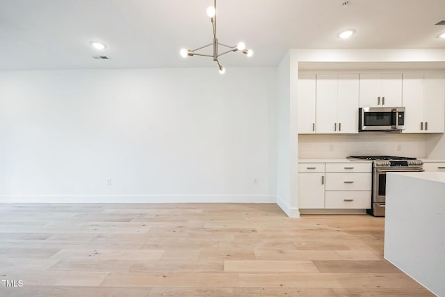 kitchen featuring visible vents, light wood finished floors, light countertops, appliances with stainless steel finishes, and backsplash