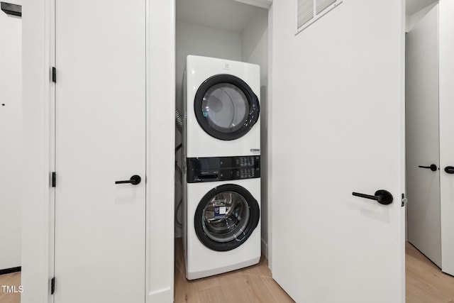 laundry room featuring visible vents, light wood-style floors, and stacked washer and dryer