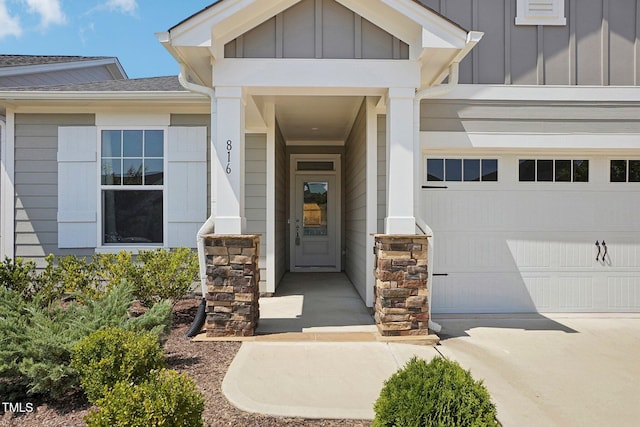 doorway to property featuring an attached garage, stone siding, and board and batten siding