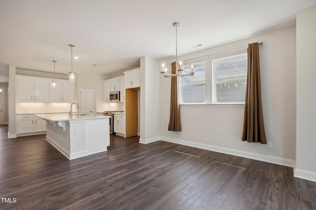 kitchen with dark wood-style flooring, backsplash, appliances with stainless steel finishes, white cabinets, and a sink