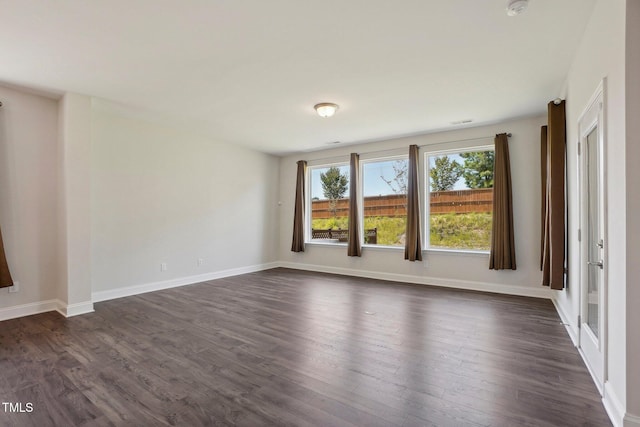 unfurnished room featuring visible vents, baseboards, and dark wood-style flooring