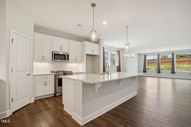 kitchen featuring appliances with stainless steel finishes, white cabinetry, a sink, and backsplash