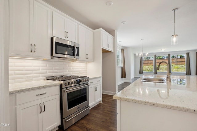 kitchen with dark wood-style flooring, decorative backsplash, appliances with stainless steel finishes, white cabinets, and a sink