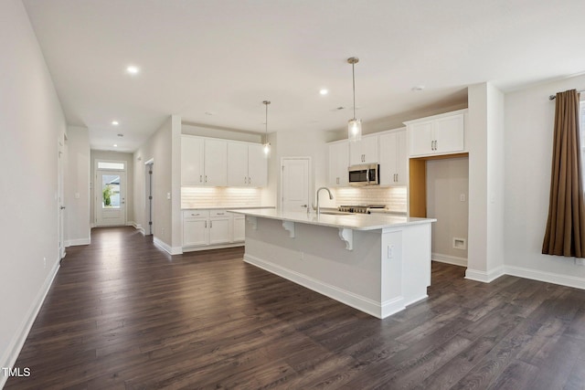 kitchen featuring dark wood-type flooring, stainless steel microwave, white cabinets, and a sink