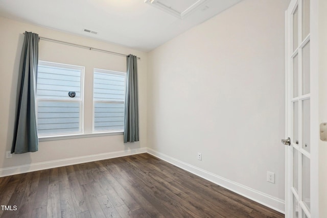 spare room featuring baseboards, visible vents, and dark wood finished floors