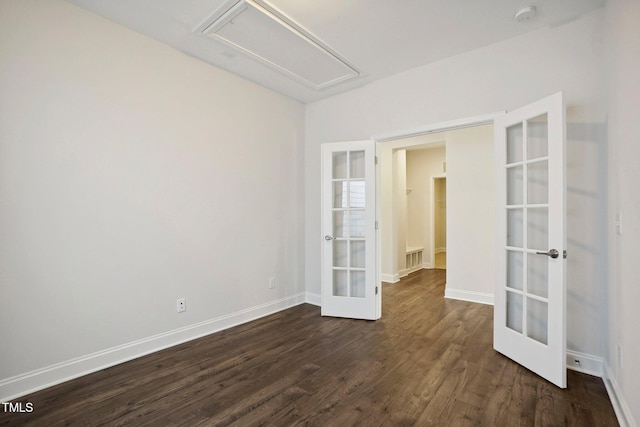 empty room featuring attic access, french doors, dark wood finished floors, and baseboards