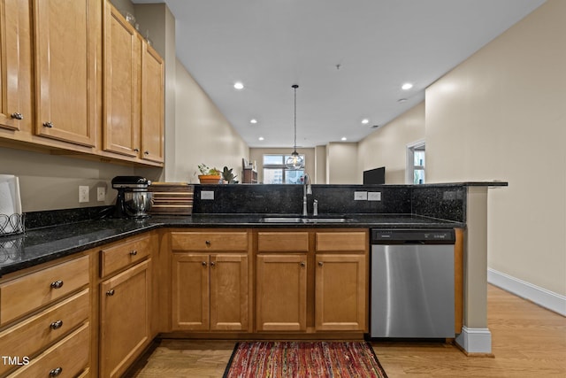 kitchen with sink, dark stone countertops, stainless steel dishwasher, kitchen peninsula, and pendant lighting