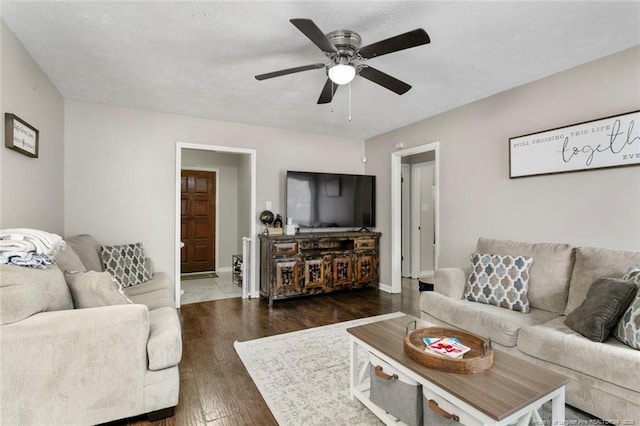 living room with dark wood-type flooring, a textured ceiling, and ceiling fan