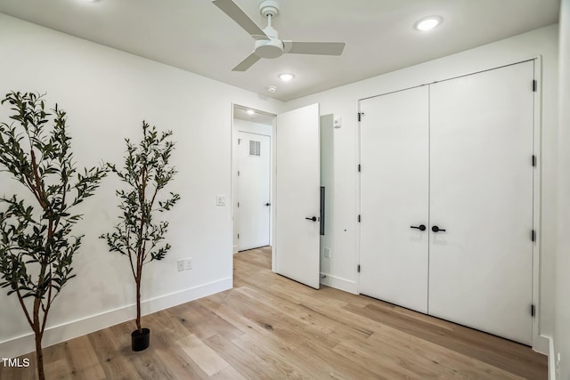 unfurnished bedroom featuring ceiling fan, a closet, and light wood-type flooring