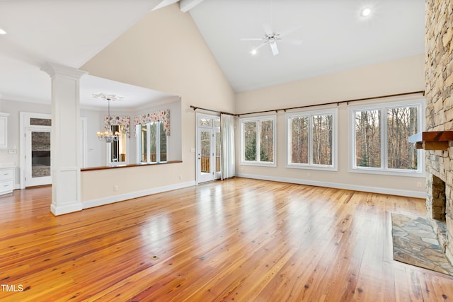 unfurnished living room featuring ornate columns, a stone fireplace, high vaulted ceiling, beamed ceiling, and light wood-type flooring