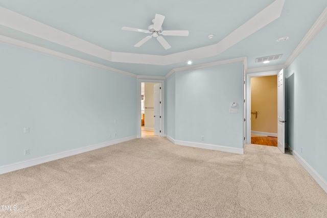 carpeted spare room with a tray ceiling, ornamental molding, and ceiling fan