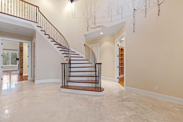 staircase with crown molding and a towering ceiling