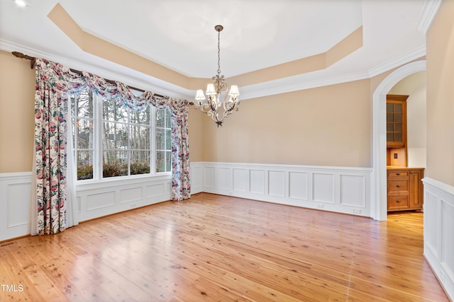 unfurnished dining area featuring ornamental molding, light hardwood / wood-style floors, and a tray ceiling