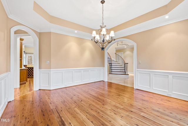 unfurnished dining area featuring crown molding, wood-type flooring, and a tray ceiling