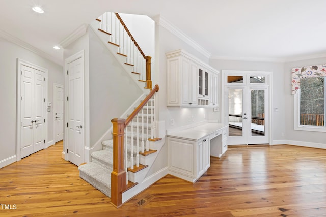 stairway with hardwood / wood-style flooring, ornamental molding, and french doors