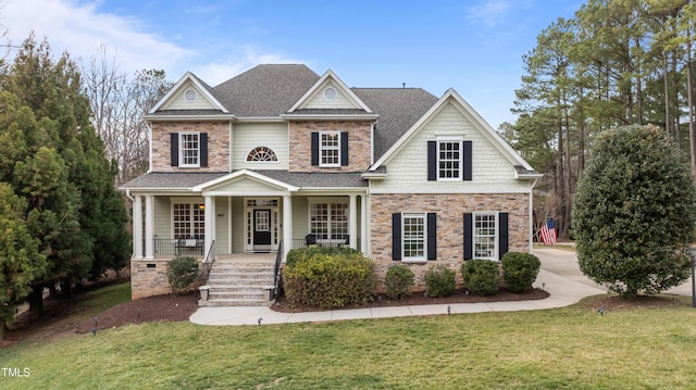 craftsman house with stone siding, a front lawn, a porch, and roof with shingles