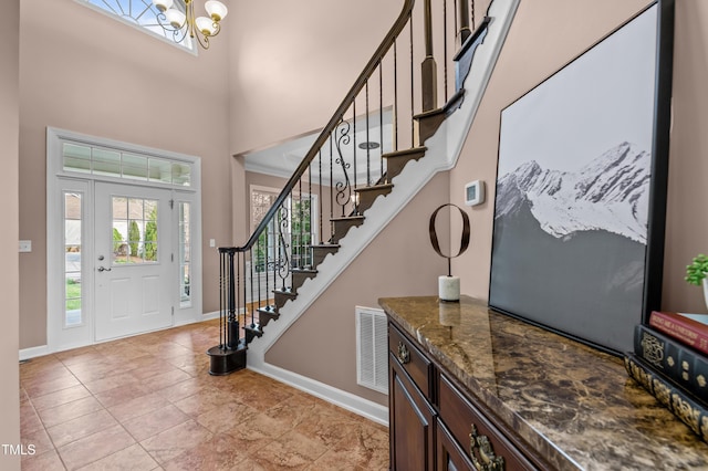 foyer featuring baseboards, stairway, a towering ceiling, and an inviting chandelier